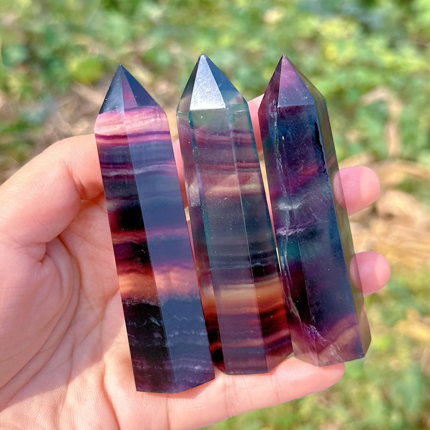 Three rainbow fluorite towers held up to the light
